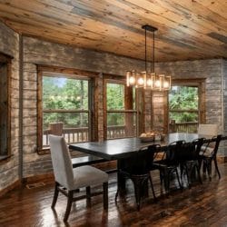 Dining table beside tall windows and a stone wall under pendant lights