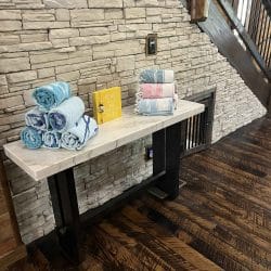 Console table with rolled towels against the stone wall beside the stairs