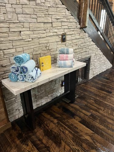Console table with rolled towels against the stone wall beside the stairs