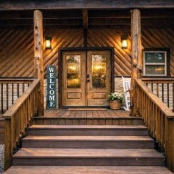 Front entry with double glass doors, a welcome sign and wide wooden steps