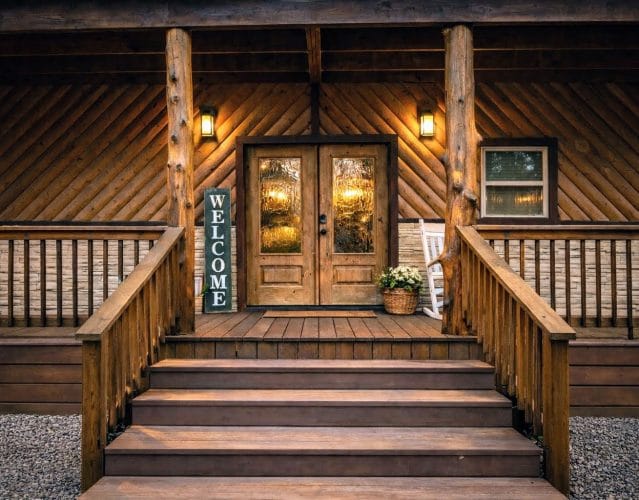 Front entry with double glass doors, a welcome sign and wide wooden steps