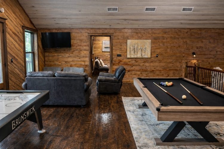 Game loft with a black-felt pool table, air hockey, a sofa and a TV