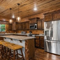 Kitchen with a granite-topped island and bar stools, stainless fridge and wood cabinets
