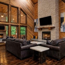 Tall living room windows beside the stone fireplace, with sofas in front