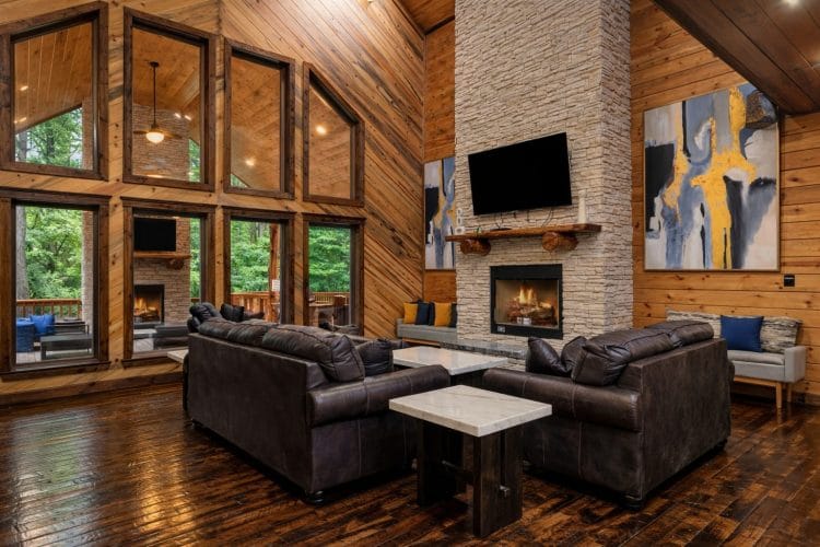 Tall living room windows beside the stone fireplace, with sofas in front