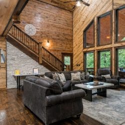Living room seating with the wood staircase and tall windows behind