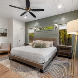 Same bedroom with a tripod floor lamp and a window beside the bed