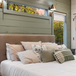 Close view of the bed with plaid and floral pillows and the green wall behind
