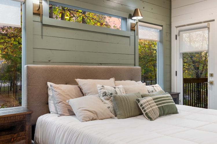 Close view of the bed with plaid and floral pillows and the green wall behind