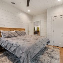 Same upstairs bedroom from the foot of the bed, with a closet door and the TV