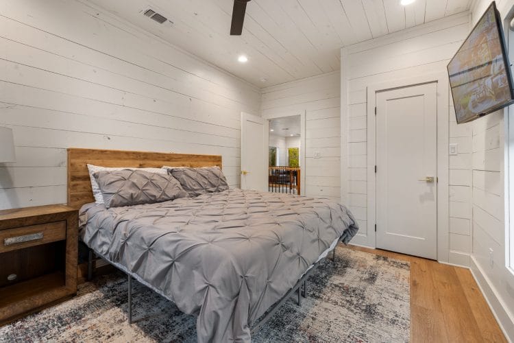 Same upstairs bedroom from the foot of the bed, with a closet door and the TV