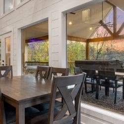 Wood dining table with X-back chairs beside a window onto the covered deck