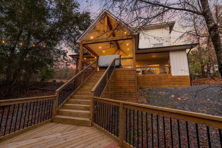 Cabin seen from the deck stairs at dusk, with the covered deck lit up