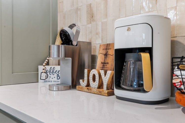Countertop coffee maker beside a wooden JOY sign