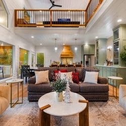 Living room with two cream sofas and a brown sofa around a round coffee table, with the loft railing and a ceiling fan above