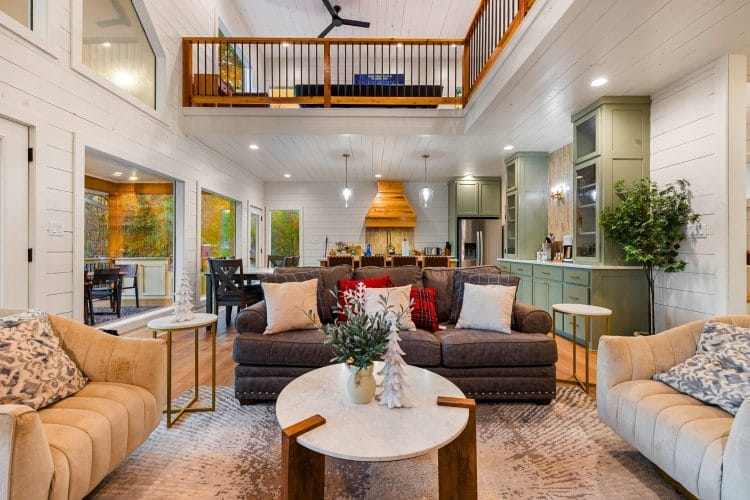Living room with two cream sofas and a brown sofa around a round coffee table, with the loft railing and a ceiling fan above