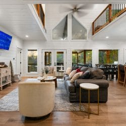 Open main room with a tan armchair and sofas, and bar stools along the kitchen counter