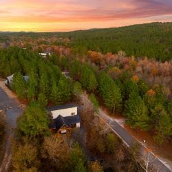 Aerial view of the cabin and gravel road through the trees at sunset