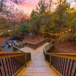 Wooden deck stairs and walkway leading down to the fire pit area, string lights above