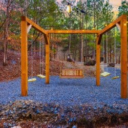 Timber swing frame with bench swings on a gravel pad