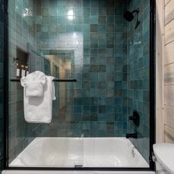Teal-tiled tub-shower with a glass door