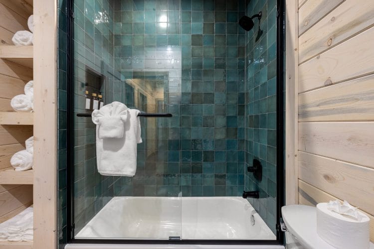 Teal-tiled tub-shower with a glass door