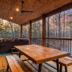 Covered deck with a wood picnic table and benches, the hot tub behind