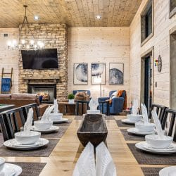 Long dining table set for a meal in front of the stone fireplace