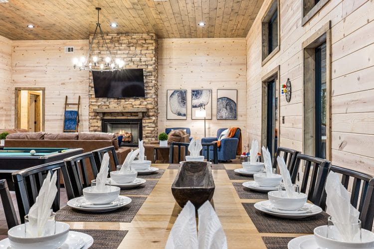 Long dining table set for a meal in front of the stone fireplace