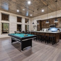 Pool table beside the kitchen island, with a dart board on the wall