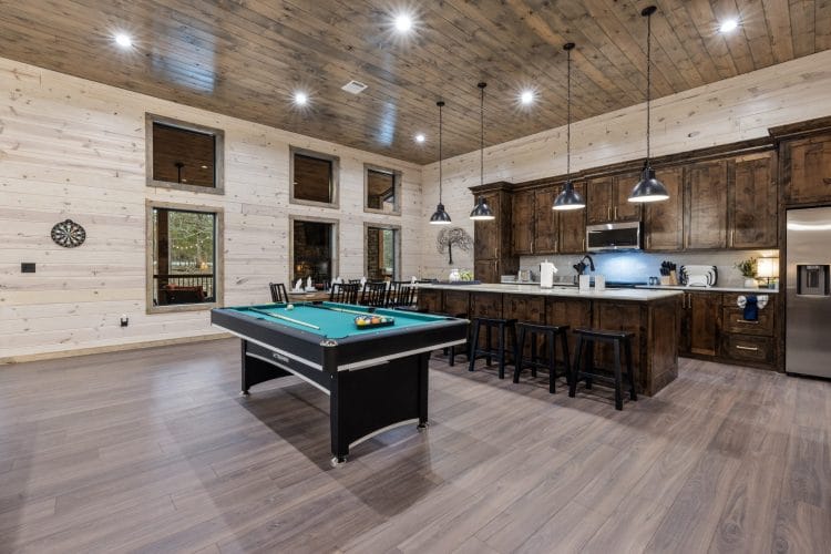 Pool table beside the kitchen island, with a dart board on the wall