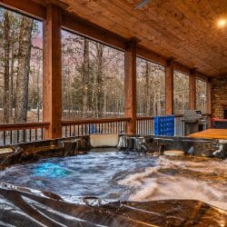 Hot tub on the covered porch with the stone fireplace in the background