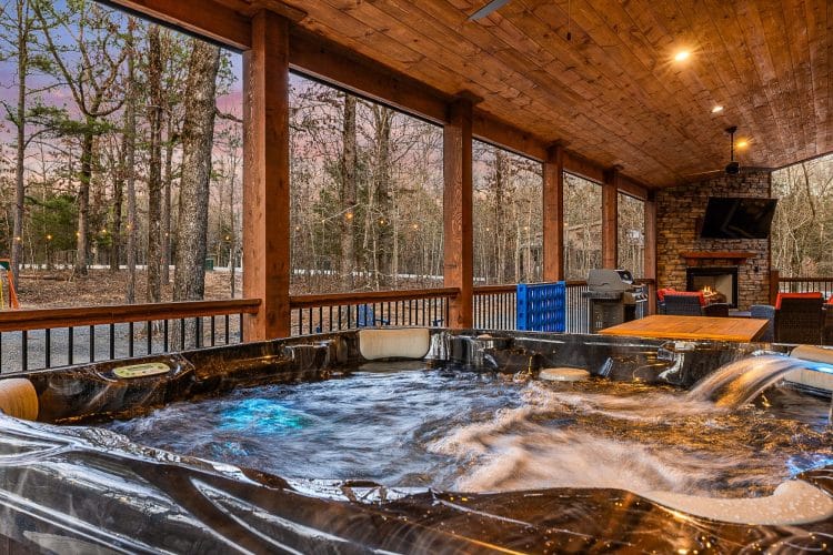 Hot tub on the covered porch with the stone fireplace in the background