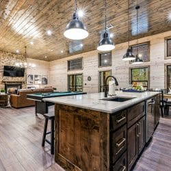Kitchen with a dark-stained island and pendant lights, the pool table beyond