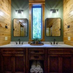 Double vanity with dark wood cabinets and two mirrors against green walls