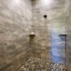 Walk-in shower with gray tile and a pebble floor
