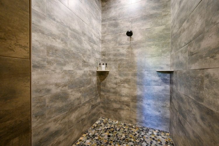 Walk-in shower with gray tile and a pebble floor
