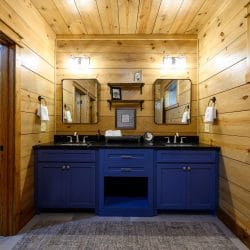 Double vanity with navy cabinets and a black top, towel shelves at the left