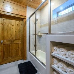 Glass-door tub-and-shower with folded towels on built-in shelves