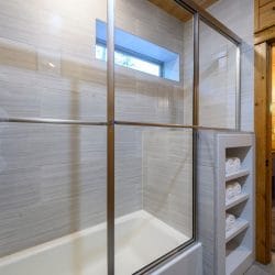 Tub-shower behind a glass door with a small window above