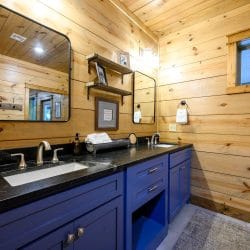 Double vanity with navy cabinets, black top and framed mirrors