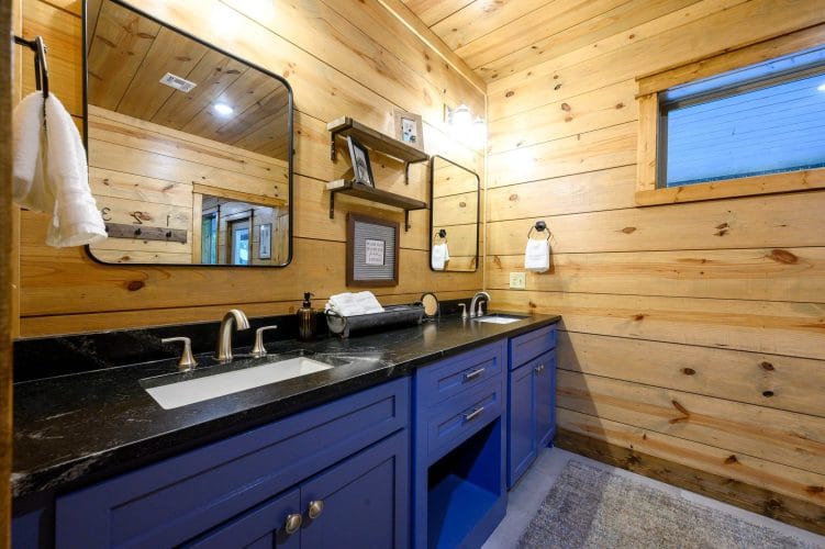 Double vanity with navy cabinets, black top and framed mirrors