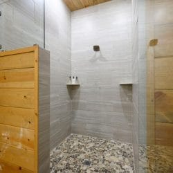 Walk-in shower with gray tile and a pebble floor