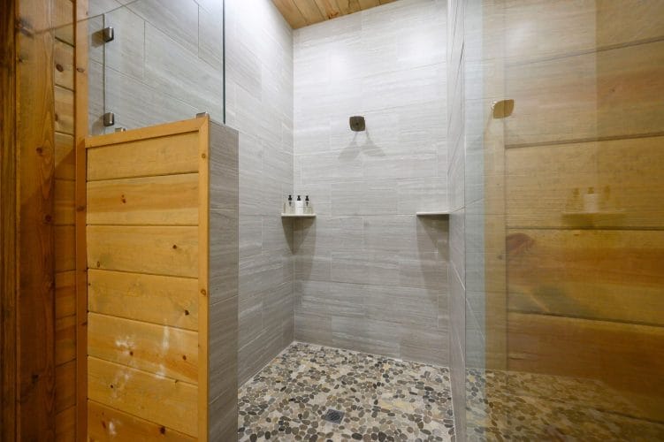 Walk-in shower with gray tile and a pebble floor