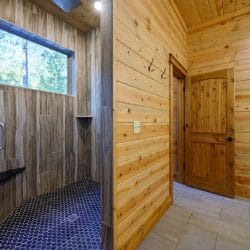 Walk-in shower with a dark hex-tile floor beside the bathroom door