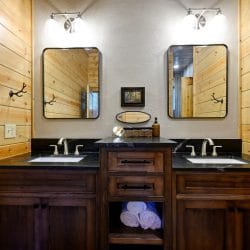 Double vanity with a black countertop and two matching mirrors