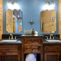 Double vanity with a dark top and two mirrors against a blue wall