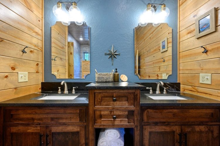 Double vanity with a dark top and two mirrors against a blue wall
