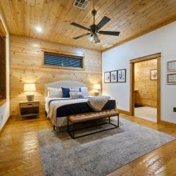 King bed with a white curved headboard, navy runner and a bench at the foot