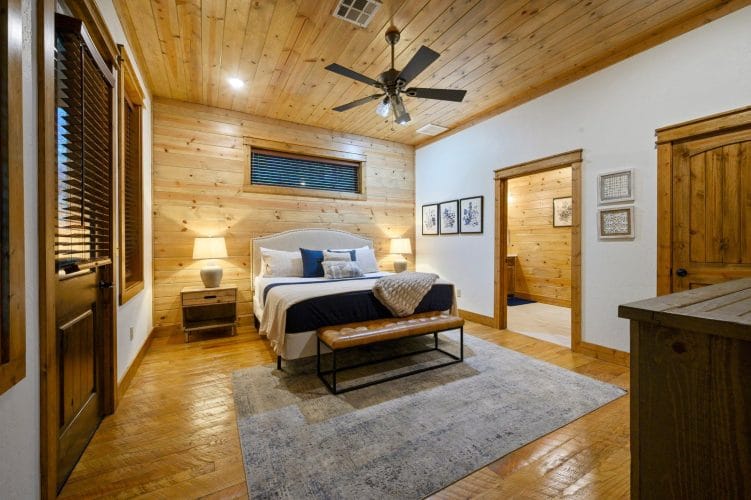 King bed with a white curved headboard, navy runner and a bench at the foot